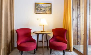 Eine Sitzecke mit zwei roten Sesseln und einem kleinen runden Tisch in der Maisonette