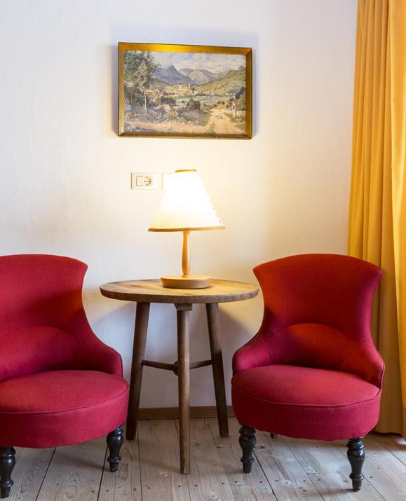 A sitting area with two red armchairs and a small round table in the Maisonette.