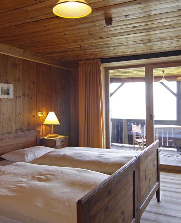 Doppelzimmer Loggia mit Holzvertäfelung, zwei Einzelbetten, einem großen Balkon und Einrichtung im rustikalen Stil