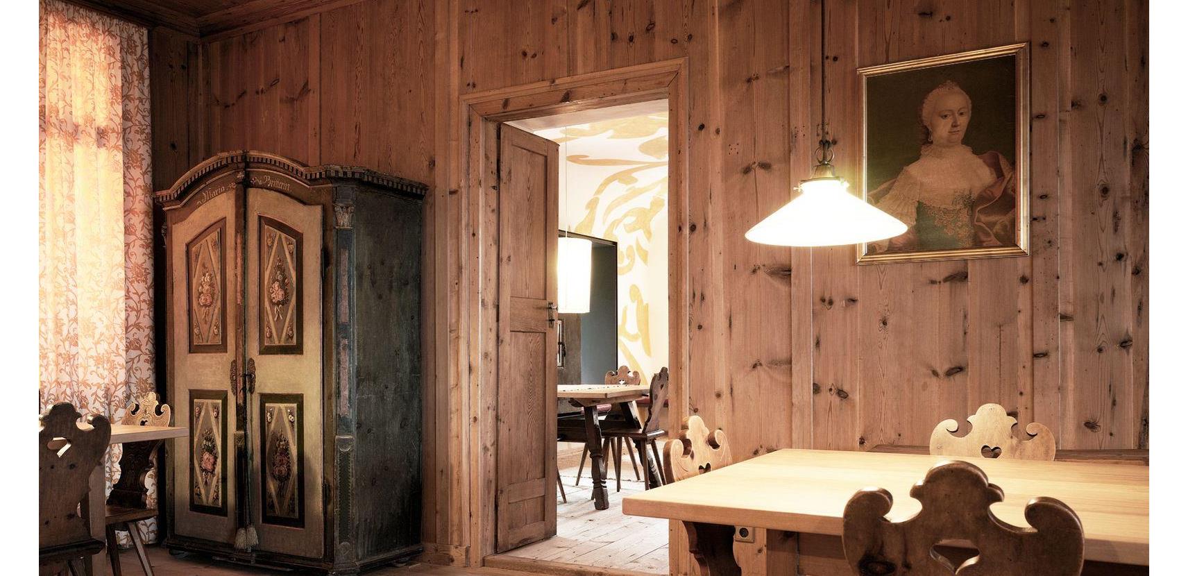 Our traditional Tyrolean Stube dining room with wood-paneled walls, carved chairs, and an antique farmhouse wardrobe