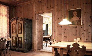 Unsere traditionelle Stube mit holzvertäfelten Wänden, verzierten Stühlen und antikem Bauernschrank
