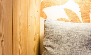 Nahaufnahme der Leseecke im Doppelzimmer Kirche: Man sieht eine eingeschaltete Leselampe und eine Ecke des Sofas mit einem Kissen.