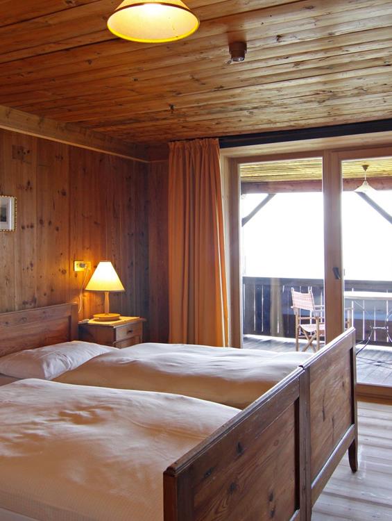 The wood-paneled Loggia double room with two single beds, a big balcony and rustic furniture