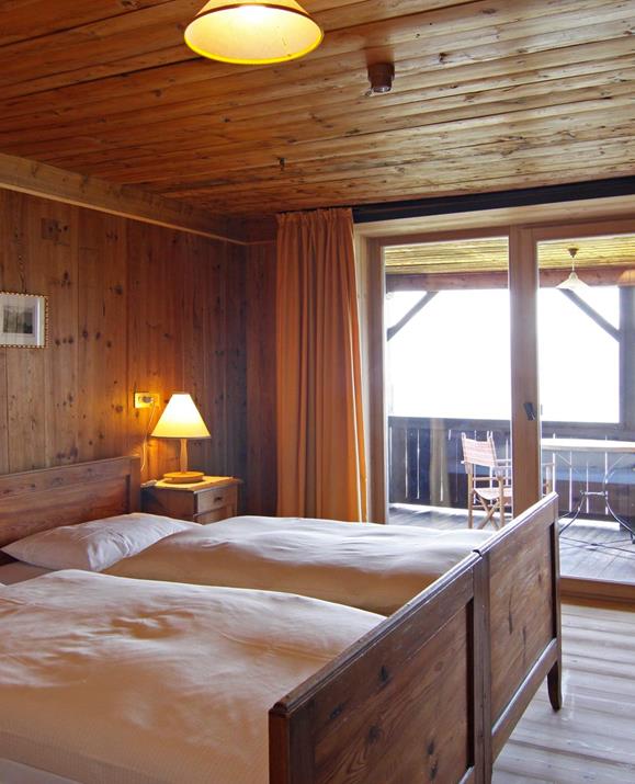 Doppelzimmer Loggia mit Holzvertäfelung, zwei Einzelbetten, einem großen Balkon und Einrichtung im rustikalen Stil